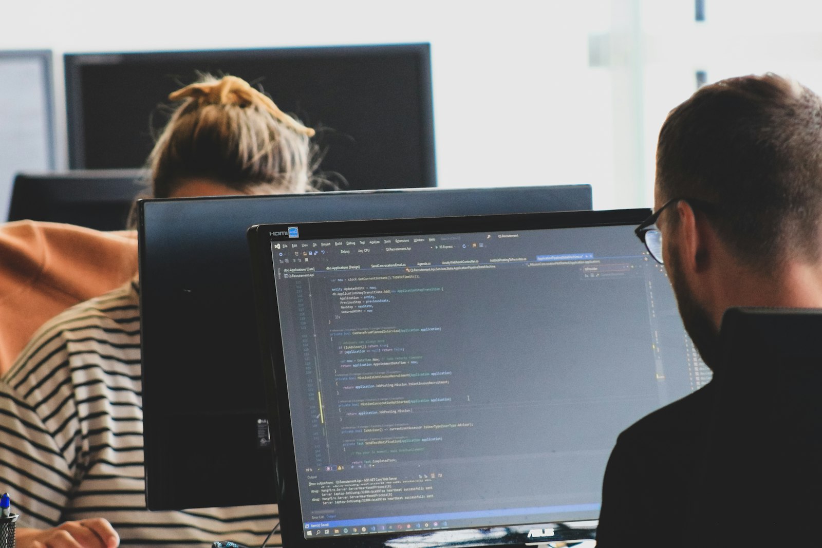 Two developers reviewing code together on desktop monitors